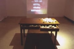 "KES SÜÜTA, VISAKU ESIMENE KIVI..." 2003 installatsioon: laud, kivid, video <br /> "WHO IS INNOCENT, ...." 2003 installation: table, stones, video